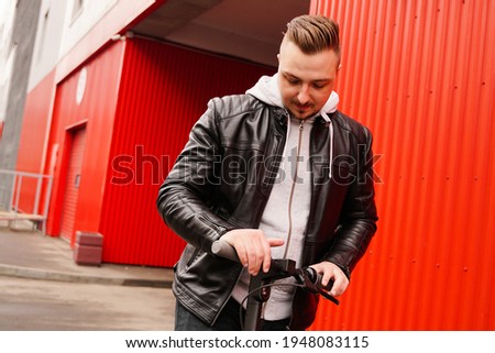 Young attractive man on electric scooter over red background