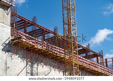 Scaffolding and rebar on a concrete wall, near the sopor of a construction crane, construction of a large building, background, 2021