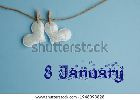 Commemorative date of January 8 on blue background with white hearts with clothespins, flat lay. Holiday calendar concept