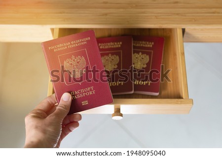 A woman hand take or put three biometric Russian passports document in a drawer, on a shelf. Travel forbidden due to coronavirus pandemic worldwide. Banned travel and tourism covid-19