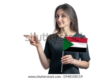 Happy young white woman holding flag Sudan and points to the left isolated on a white background.