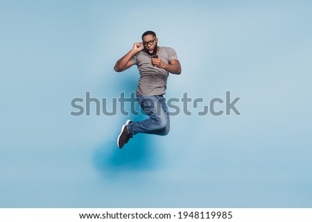 Full size photo of afro american guy jump cellphone isolated blue color background