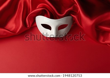 White theatre mask and fabric on red background, above view. Space for text