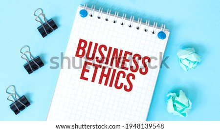 White notepad with text Business Ethics and office tools on the blue background