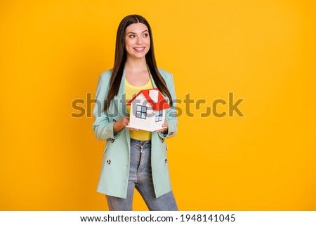 Photo of young happy positive smiling cheerful lovely girl moving holding small house isolated on yellow color background