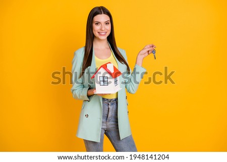 Photo of young happy cheerful smiling positive girl moving to new house hold keys isolated on yellow color background