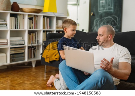 father and son using laptop computer at home.