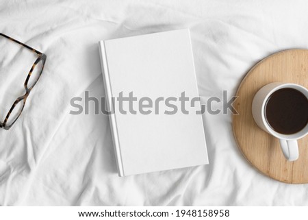 White book mockup with a cup of coffee and a glasses on the bed. Royalty-Free Stock Photo #1948158958