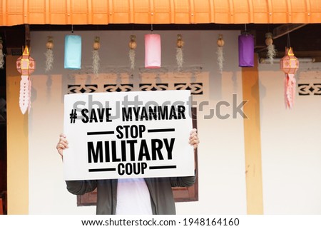 Text "Save Myanmar stop military coup" on paper sign hold by a man. Concept protest the violence from the coup in Myanmar. Royalty-Free Stock Photo #1948164160