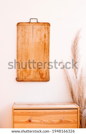 Wooden cutting board on a wall with a wooden cupboard and pampas grass for it, nordic mood and design.