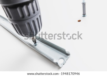 Electric screwdriver mount metal roller guides to chipboard Royalty-Free Stock Photo #1948170946