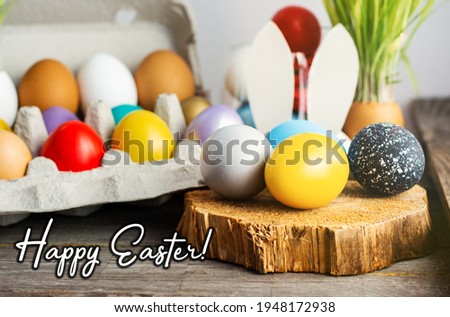 Happy Easter card. colored blue, beige, white Easter eggs in nest top view on wooden background with spring flowers, selective focus image.