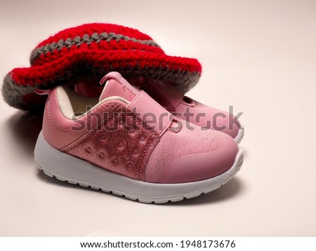 Picture of red color with grey stripes crochet hat and a pair of pink shoes. Shoot on isolated white background