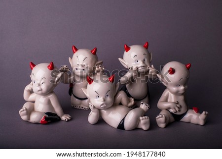The cute emotional devils statues on the deep grey background
