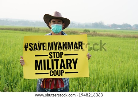 Text "#Save Myanmar stop military coup" on paper sign hold by Asian man. Concept protest the violence from the coup in Myanmar. Fight for democracy. Royalty-Free Stock Photo #1948216363