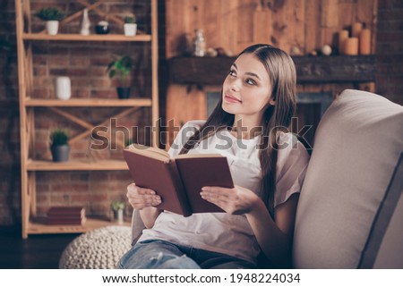 Photo of young attractive girl happy positive smile sit sofa home relax read book story novelty interested curious