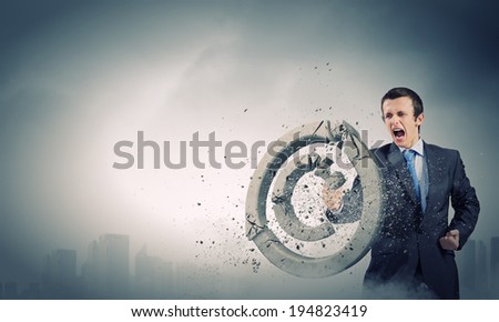 Angry businessman crashing stone trademark with karate kick