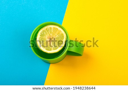 Green tea cup with lemon slice on yellow blue background,top view