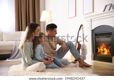 Happy family resting near fireplace at home