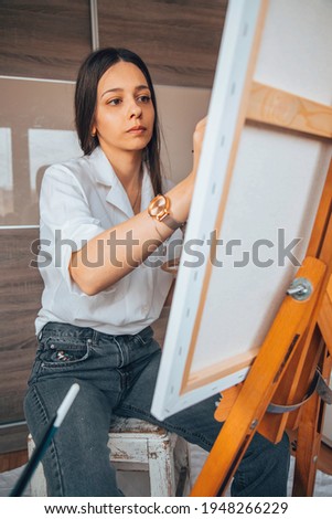 Beautiful talented female artist painting at her home. Focus on girl.