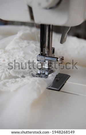 Close up of a sewing machine making alterations of a bride's wedding dress. Royalty-Free Stock Photo #1948268149