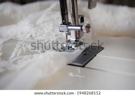 Close up of a sewing machine making alterations of a bride's wedding dress. Royalty-Free Stock Photo #1948268152