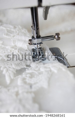 Close up of a sewing machine making alterations of a bride's wedding dress. Royalty-Free Stock Photo #1948268161
