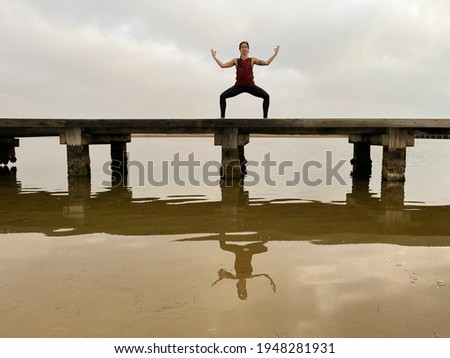 Young woman practices yoga on a lake