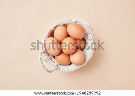 Basket with homemade eggs centered in the middle of the picture on beige background.