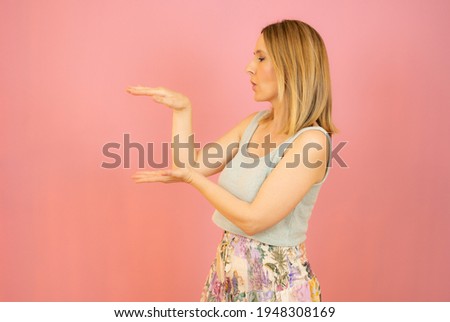 Young woman over isolated background holding something with both hands, product presentation.
