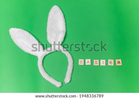 white rabbit ears on a green background. Easter greeting card inscription easter Happy Easter. Copyspace is a place for text. A greeting card. Rabbit ears. Monotonous green background for the label.