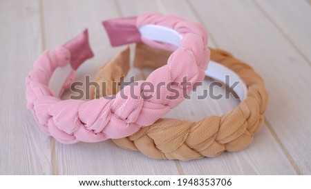 Soft pink and brown color braided headband made out of chiffon and tulle fabric texture. A hair band or headpiece with braid pattern.