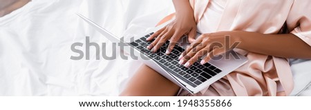 Cropped view of african american freelancer using laptop on bed, banner