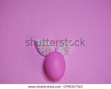 Pink egg and pink bunny ears on pink background - top view. Happy Easter day.
