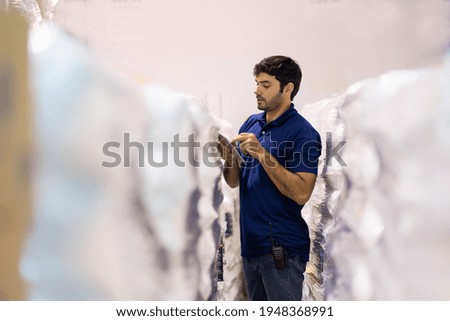 Male employee warehouse worker using digital tablet checking products or parcel goods in industry factory warehouse. Inspection quality control