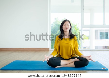 Asian women are doing yoga at home to make a good body.