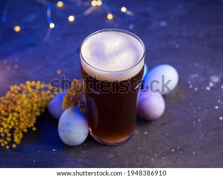 Limited edition craft beer pint glass on blue background, painted Easter eggs. The concept of celebrating Easter