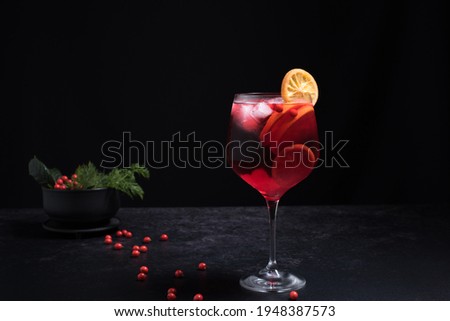 Red cocktail glass decorated with orange slice on black background