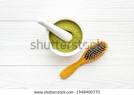 Henna hair dye powder and wooden comb. Henna in wtite mortar