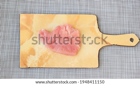 A raw piece of turkey fillet on a chopping board. Top view.