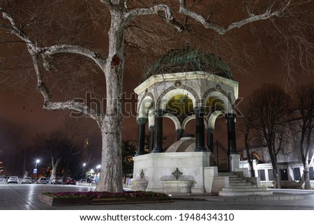 The German Fountain is located on the Sultanahmet Square also known as the Square of Sultan Ahmed in Istanbul. There is large old tree with a pale bark close to the fountain. Night in Istanbul.