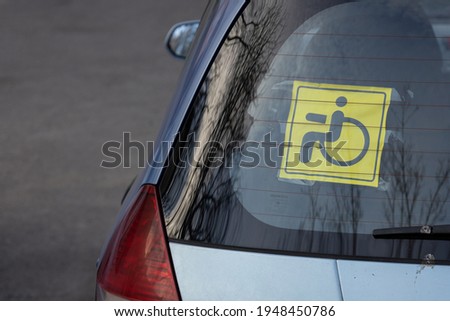  Attention sign, person with disability inside. Yellow and black sticker with a wheelchair symbol on stuck to the inside of the rear car window. Close up