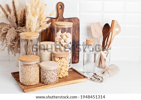 Assortment of grains, cereals and pasta in glass jars and kitchen utensils on wooden table. Healthy balanced food, sustainable lifestyle, zero waste storage, eco friendly idea Royalty-Free Stock Photo #1948451314