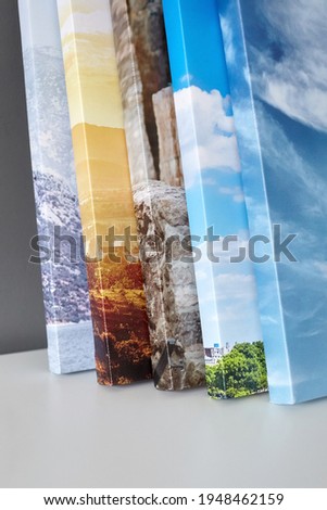 Canvas prints stacked on white surface on grey wall background. Photo printed on canvas. Stretched photographs with gallery wrapping