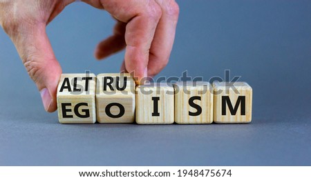 Altruism or egoism symbol. Businessman turns wooden cubes and changes the word 'egoism' to 'altruism'. Beautiful grey background, copy space. Business, psychological and altruism or egoism concept.
