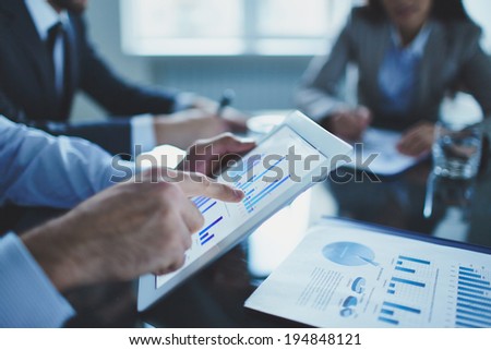 Image of businessperson pointing at document in touchpad at meeting