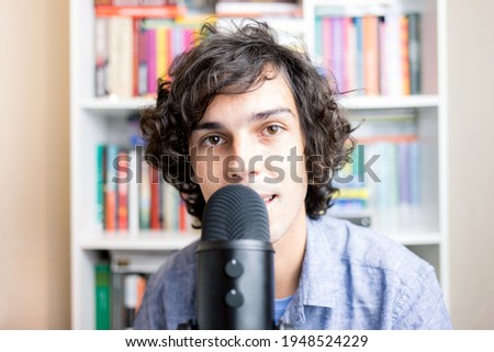 Portrait of a young man recording a podcast or making a live streaming. Young man speaking into a microphone.