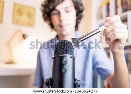 Brush touching the microphone. Young making ASMR sounds with the movement of a makeup brush. Concept of recording sounds to relieve stress.
