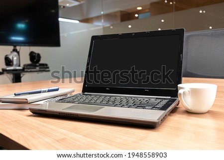 Laptop display blank on table in meeting room.