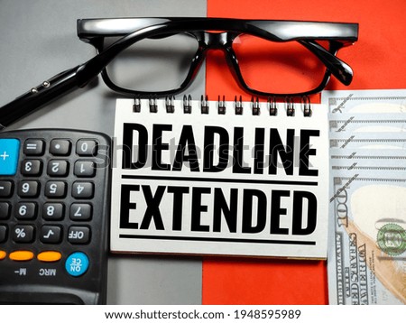 Business concept.Text DEADLINE EXTENDED with glasses,calculator,pen and banknote on gray and red background.